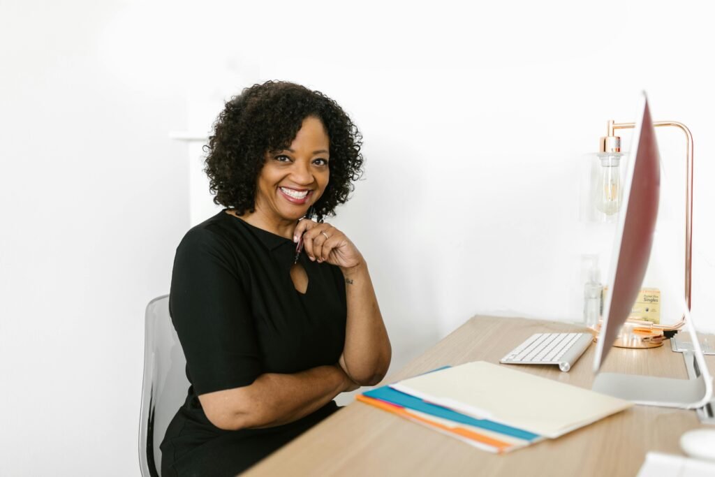 Happy woman sitting at a desk in a bright modern office, smiling confidently.