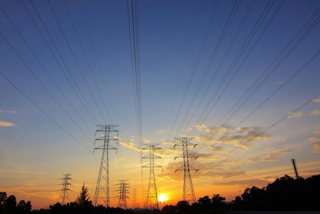 Transmission towers crossing a vibrant sunset sky, symbolizing energy and connection.